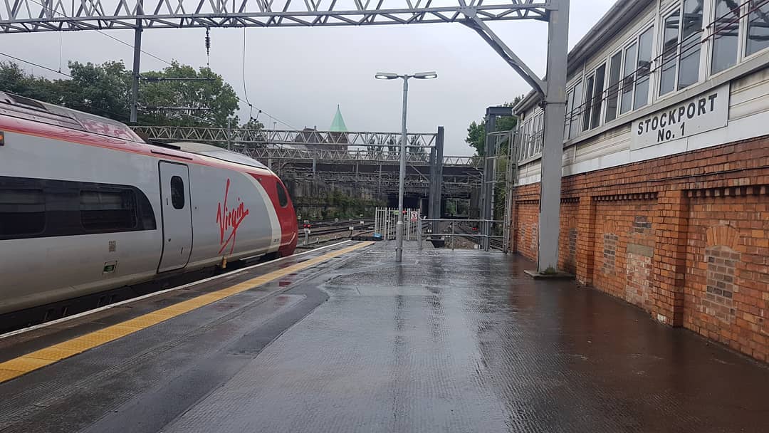 A Virgin Trains Class 390 'Pendolino' sits in platform 3 at Stockport railway station on a rainy afternoon. Looking south, the train is to the left of the Stockport Number 1 signal box.
